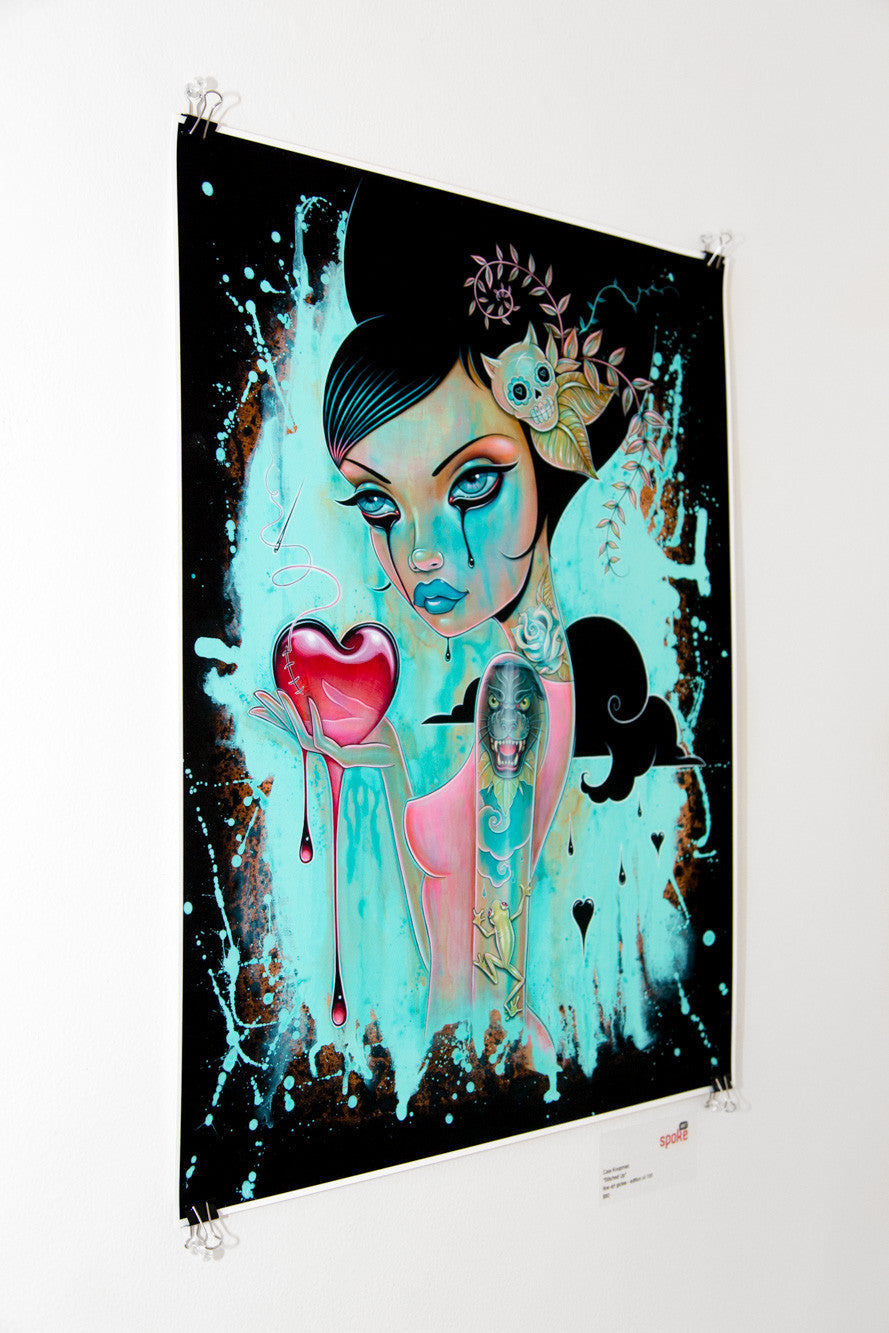 This limited edition archival pigment print by Caia Koopman features a stylized female figure with bold eyes and tears, holding a dripping heart. Bright teal and pink hues dominate the background with intricate floral and skull motifs.
