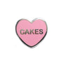 Candy heart style enamel pin with CAKES written on it
