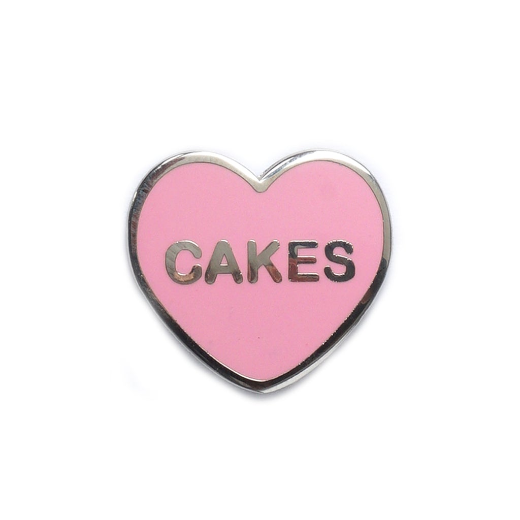 Candy heart style enamel pin with CAKES written on it