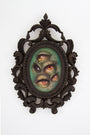 The ornate dark frame holds Tatiana Suarezs Through the Veil, an oil on canvas featuring multiple eyes in vibrant yellow and orange against a green textured background, creating an otherworldly, surreal effect with their varied sizes and orientations.