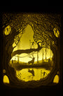 Hari & Deeptis intricately crafted cut paper art piece illustrates an enchanted landscape. A deer stands by a pond surrounded by tangled trees, as warm yellow light filters through, creating a magical ambiance.
