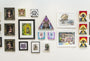 A gallery wall by Joemur presents an eclectic mix of artworks, prominently featuring vibrant cat styles. The collection includes both framed and unframed pieces in unique shapes like triangles and a playful ballpoint pen drawing reminiscent of a Lil Bub show.