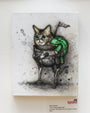 An illustration from Kaitlin Beckett features a cat with expressive eyes and mechanical legs in sci-fi armor, holding a green toy lizard. A BUB flag hints at Time Traveling Space Bub escapades against a gray, ink-splattered background reminiscent of the original Lil Bub art exhibit.