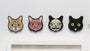 Four cat face illustrations by Matt Ritchie line the wall: a full face, muscle anatomy, skull anatomy, and a black silhouette with bright yellow eyes that evokes Lil Bub art charm.