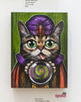 An original whimsical painting of a fortune-teller cat in a purple hat and red robe, with a crystal ball swirling in green and purple, set against green. It perfectly complements the Kelly Vivanco art exhibit in the gallery.