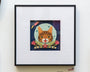 The Cat From Outer Space, a charming collage by Meghan Stratman, showcases a cat in a space helmet surrounded by flowers, with a rocket soaring beside the moon in the background.