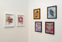 A corner display features six framed abstract artworks by Ryan De La Hoz: on the left, two vibrant swirl pieces in white frames evoke hand-marbled paper; on the right, four black-framed pieces present diverse patterns and textures against a white wall.