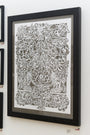 Elaine Penwells framed hand-cut paper art from the Menagerie Collection showcases exquisite floral and animal designs in predominantly white with black outlines, elegantly displayed on a wall.