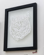 Elaine Penwells framed artwork displays an intricate hand-cut paper design of a tigers head on white. The black frame highlights the detailed fur and facial features, with the Spoke Art logo in the corner, inspired by 1984 artistry.