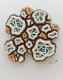 This wall-mounted abstract art piece from Charles Clary showcases layered organic shapes with intricate cutouts. The layers, in hues of white, orange, red, and green, evoke geological or cellular patterns and cast delicate shadows on the wall.