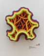 A layered sculpture by Charles Clary, resembling a stylized topographic map, showcases vibrant contours in yellow, orange, and purple. Crafted with hand-cut paper on acrylic panel, it casts intricate shadows against a pale wall. Text beside it includes the artists name and artwork details.