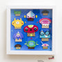 A vibrant Crowded Teeth framed artwork depicts cartoonish mushroom characters on a blue background, embodying a whimsical Mushroom Village. Each mushroom has distinct expressions and designs, such as one with glasses and another with a rainbow cap, labeled Spoke Art in the bottom right.