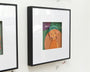 Meghan Stratmans modern framed art features a stylized illustration of a person in a green hat on a white wall. The elegant black frame and minimalistic style, incorporating an intriguing paper collage element, enhance its visual appeal.