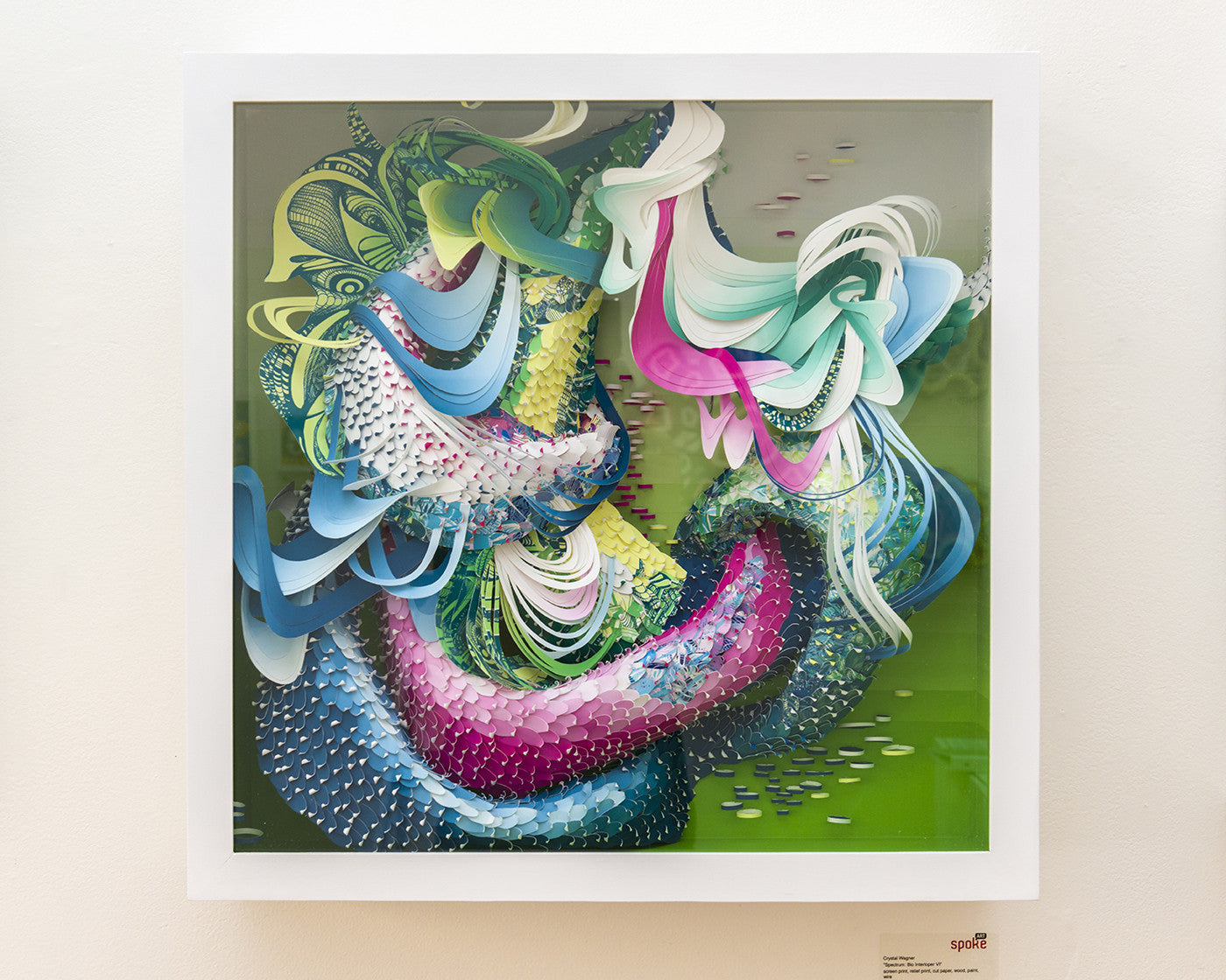 Bio Interloper VI by Crystal Wagner is a vibrant abstract screen print in a square white frame. It features swirling shapes in vivid pink, blue, green, and white on a light background, creating an impression of depth and movement.