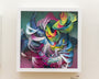 A vibrant abstract artwork with a 3D effect, echoing Crystal Wagners style, features swirling ribbons and geometric shapes in pink, blue, yellow, and green within a square frame.