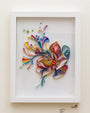 This Yulia Brodskaya framed artwork features a colorful paper quilling design with hand-cut swirls of blue, red, yellow, and green forming floral and abstract patterns. Intricate circular elements provide detail against a white background inside the white frame.