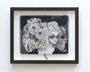 Framed artwork by the brand Tatiana Suarez showcases a monochrome sketchbook illustration of a stylized person with long hair, encircled by intricate flowers and gold accents on a dark backdrop.