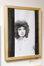 Kate Copelands framed black and white pencil sketch on Bristol board illustrates a woman with voluminous hair in profile. A black strip partially obscures the wall-mounted artwork, adding an intriguing visual element.