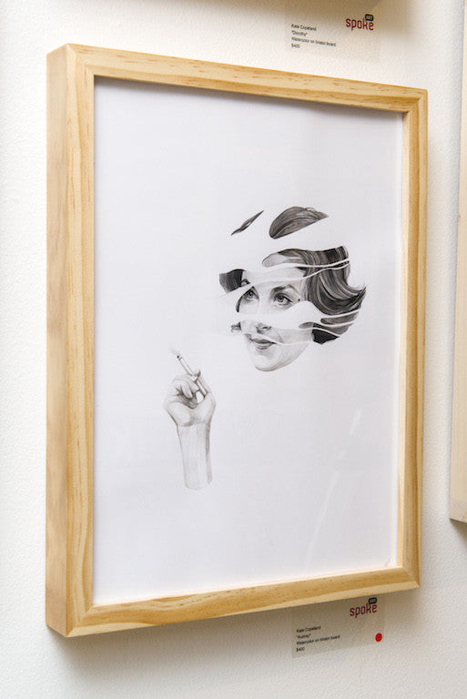 Kate Copelands framed artwork showcases a surreal pencil drawing on Bristol board, depicting a woman with fragmented facial and hand features. The wooden frame beautifully complements the disjointed design, enhancing its gallery-worthy appeal.