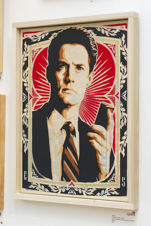 Epyon5s framed artwork depicts a serious man in a suit with a device, set against red and white patterns. This open edition uses hand-cut stencils, featuring an ornate border and vintage poster style for an eye-catching look.