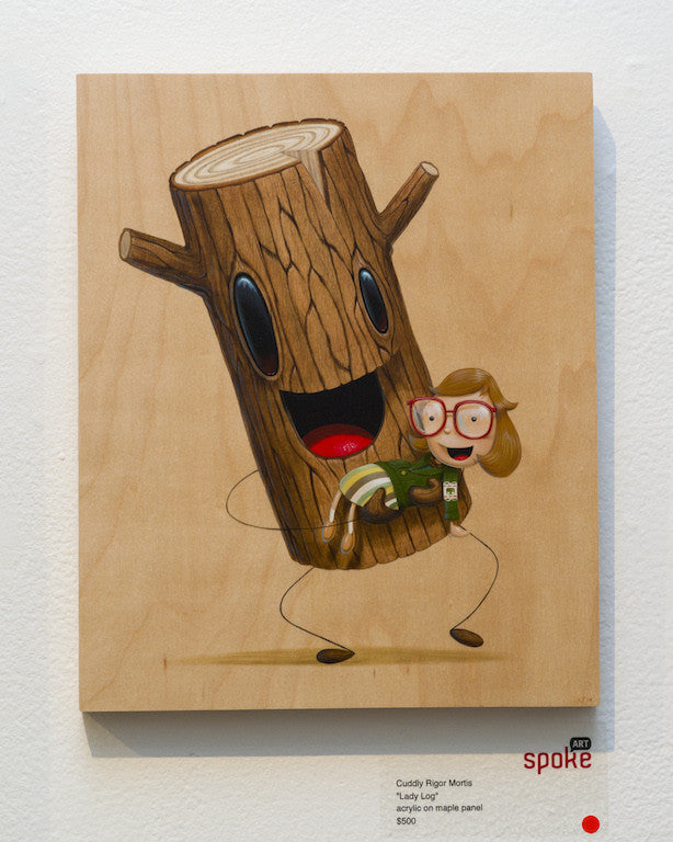 The Cuddly Rigor Mortis artwork features Lady Log, a smiling cartoon-like log holding a joyful character with glasses and brown hair. The piece is acrylic on a maple panel, elegantly mounted on a wooden wall display.