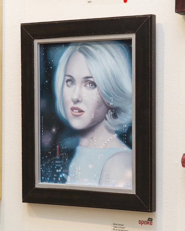 The portrait Upon a Dream by Sarah Joncas features a light-haired woman set against a starry background. She wears a light blue top and pearl necklace, capturing an ethereal, dreamy style reminiscent of Joncas signature oil on canvas masterpieces.