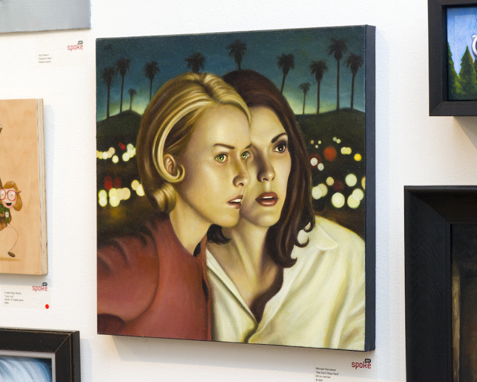 This captivating oil on canvas by Michael Ramstead showcases two women gazing intensely in unison, set against a blurred backdrop of palm trees and lights. Displayed on a gallery wall, its an intriguing artwork for sale.