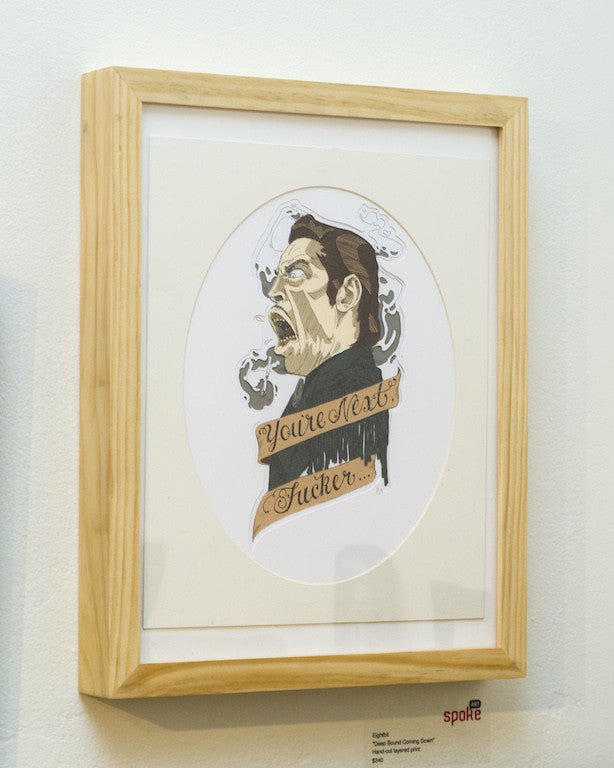 A framed artwork by Eightbit features an eight-bit style portrait of a person with an open mouth and the bold text Youre Next Fucker on a ribbon. The light background and wooden frame create an intriguing piece reminiscent of Deep Sound Coming Down.