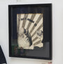 Rodrigo Cifuentes artwork features a man with exaggerated facial features in a suit and tie, set against a striped white and gray background. The piece, labeled I am a man, blends monochrome with liquid graphite for a surreal effect, suggesting digital distortion.