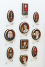 An art exhibit displays nine small round portraits alongside various shapes and designs on a white wall. Created by Evan Harris in mixed media, each piece is tagged spoRE beneath it, showcasing diverse styles and expressions.
