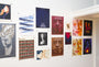 A wall display of Max Dalton fine art giclee posters showcases geometric designs, abstract portraits, colorful graphics, stylized faces, film imagery, and text elements in an eclectic layout.