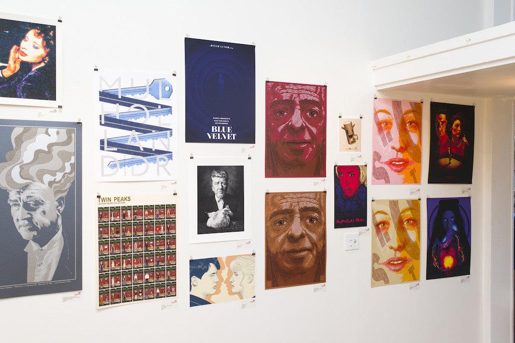 A gallery wall displays an assortment of Cuddly Rigor Mortis posters, showcasing movie themes and artistic portraits in bold colors and styles, all pinned against a white background.