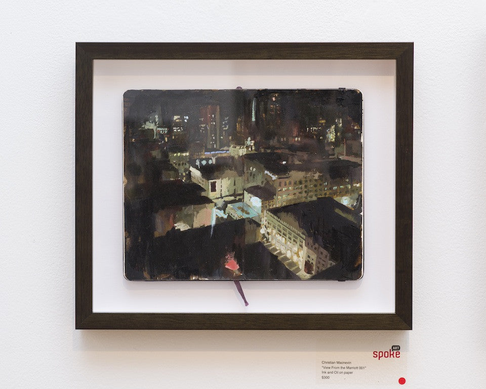 Christian MacNevins View From the Marriott is a framed artwork featuring an urban nighttime scene in ink and oil on an open sketchbook. The black-framed piece, showcasing vivid city lights and buildings, elegantly rests on a white wall with exhibit information below.