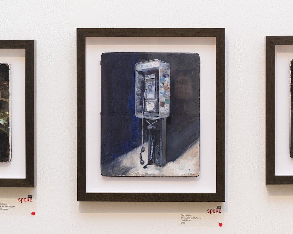 Ryan Malleys Oil on Paper, featuring vintage payphone artwork, hangs on a white wall with a dark background and subtle lighting, displayed at Spoke Art Gallery with visible price tags and labels.