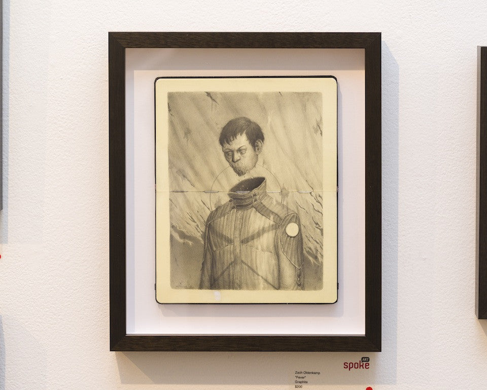 A framed artwork by Zachary Oldenkamp shows a man in a futuristic outfit with a distorted neck, set against an abstract swirling background, sketched with graphite detail. It features a simple black frame mounted on a white wall—ideal for art enthusiasts looking to 구매하게.
