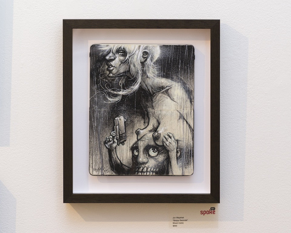A framed monochrome mixed media artwork by Jon Wayshak titled Sloppy Seconds captures a surreal scene of a humanoid figure on a creatures head, holding a gun. This striking piece is displayed in the gallery with art for sale against a white wall.