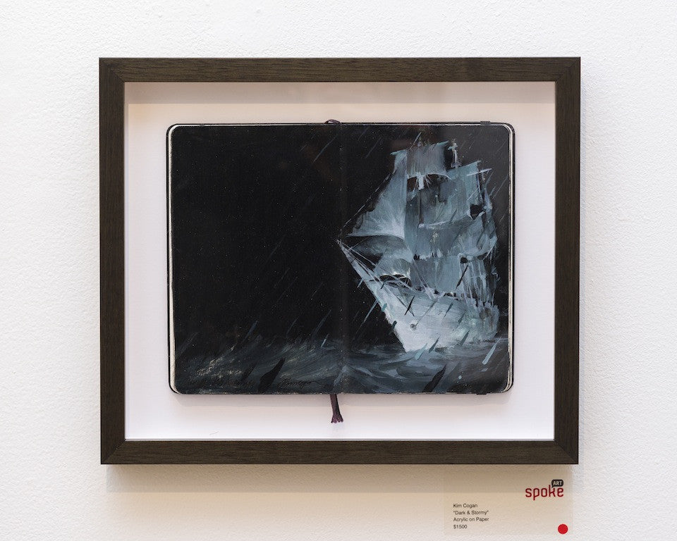 A framed Kim Cogan art piece captures a dark, stormy scene in acrylic on paper: a ship weathering waves and rain under flashes of light, with a small red dot on the frames corner.