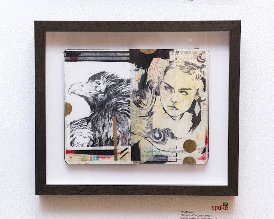Framed artwork by Nimit Malavia featuring a split design: a detailed graphite eagle on the left and a womans face with intricate lines and abstract elements on the right. This captivating collage is in a white mat and dark frame.