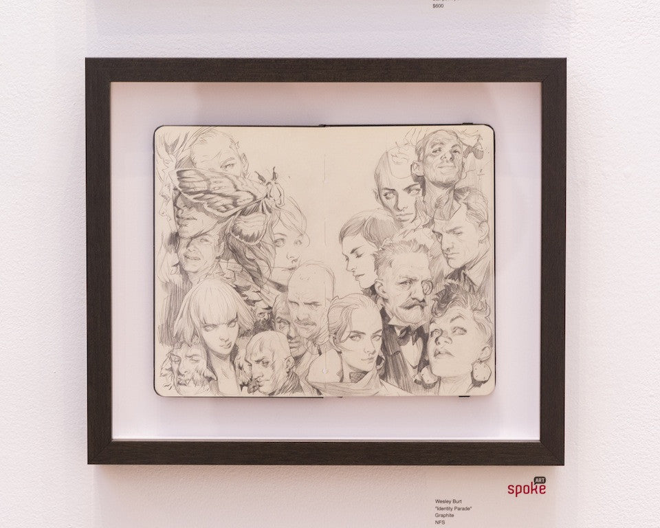 Framed artwork by Wesley Burt features a detailed pencil sketch with realistic and surreal elements, showcasing various male and female faces alongside abstract creatures in an intriguing identity parade.