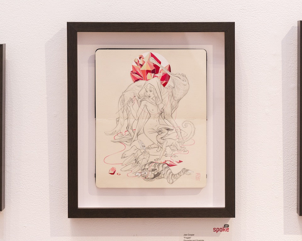 A sketch-style framed artwork by J.A.W. Cooper depicts a fantasy scene with a nude humanoid figure with animal features surrounded by a wolf, rat, and cat, holding a red geometric gem-like object.