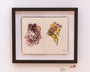 A framed open notebook by Ville Ericsson showcases two vibrant sketches of women, one with a violin and the other adorned with flowers in her hair, capturing the introvert-extrovert art style.