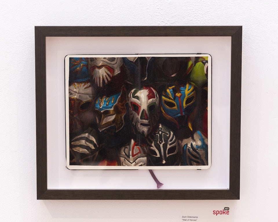 Vibrant luchador masks with intricate patterns adorn framed artwork, while a tablet displays additional masks against a Wall of Heroes. This piece beautifully captures the lively essence characteristic of Zachary Oldenkamps masterpieces.