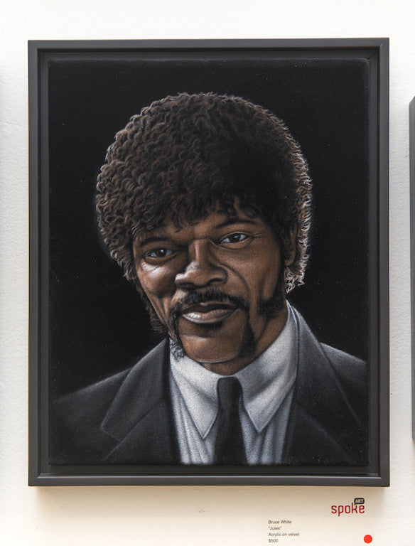 A framed painting of a man with dark curly hair and sideburns in a black suit and white shirt, crafted in acrylic on velvet. On display are the words Bruce White and Spoke, exuding cinematic intrigue reminiscent of Quentin vs Coen.