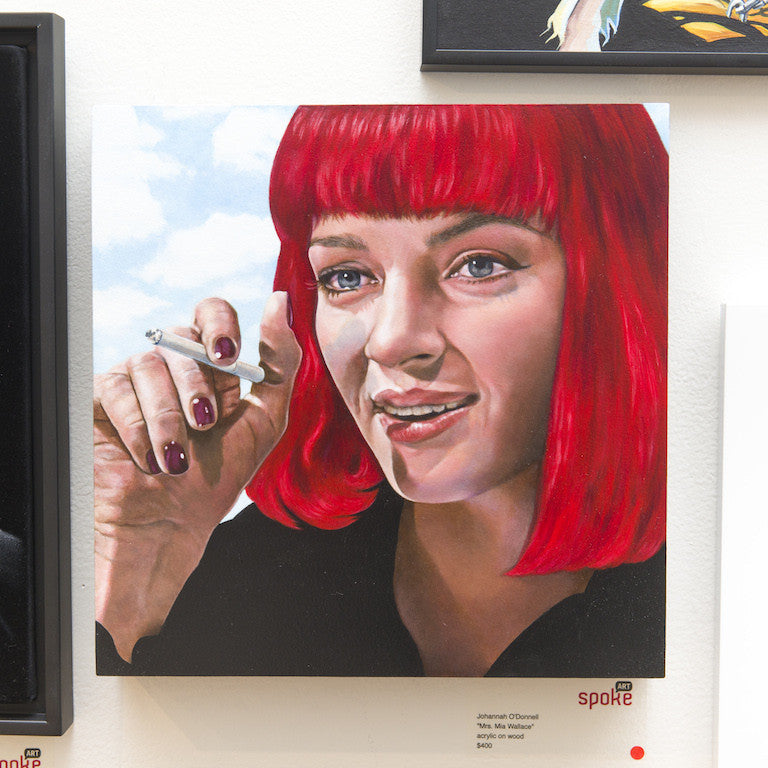 Johannah ODonnells captivating acrylic on wood painting features a woman with red hair and bangs holding a cigarette, wearing a black top and a subtle smile against a cloudy sky, reminiscent of Mrs. Mia Wallace. Displayed prominently on the gallery wall, it mesmerizes all passersby.