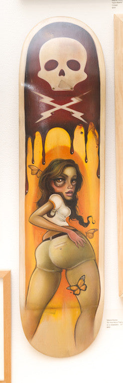 The Tatiana Suarez skateboard deck displays a surreal illustration of a woman with butterflies, above whom a paint-dripping skull is featured. The background gradient shifts from orange to brown, creating an art gallery masterpiece reminiscent of oil on skatedeck artistry.