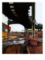 An urban scene unfolds under an elevated railway with graffiti-covered walls and pillars, industrial and red-brick buildings framing the view. Puddles reflect the tracks above, while the overcast sky adds to a moody atmosphere reminiscent of a Jessica Hess fine art giclee.