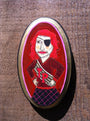 An Evan Harris mixed media painting showcases a red-haired person in a pirate outfit with an eyepatch, set within an oval frame. They wear a red JP jacket and stand confidently against a wooden backdrop.
