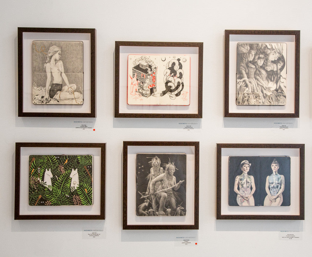 Six custom framed artworks by Ryan Lee are showcased on a white wall. The collection includes pencil on Moleskine drawings and illustrations featuring human figures, abstract designs, and tropical leaf patterns, with some pieces inspired by the Worldbridge Quartets harmonies.
