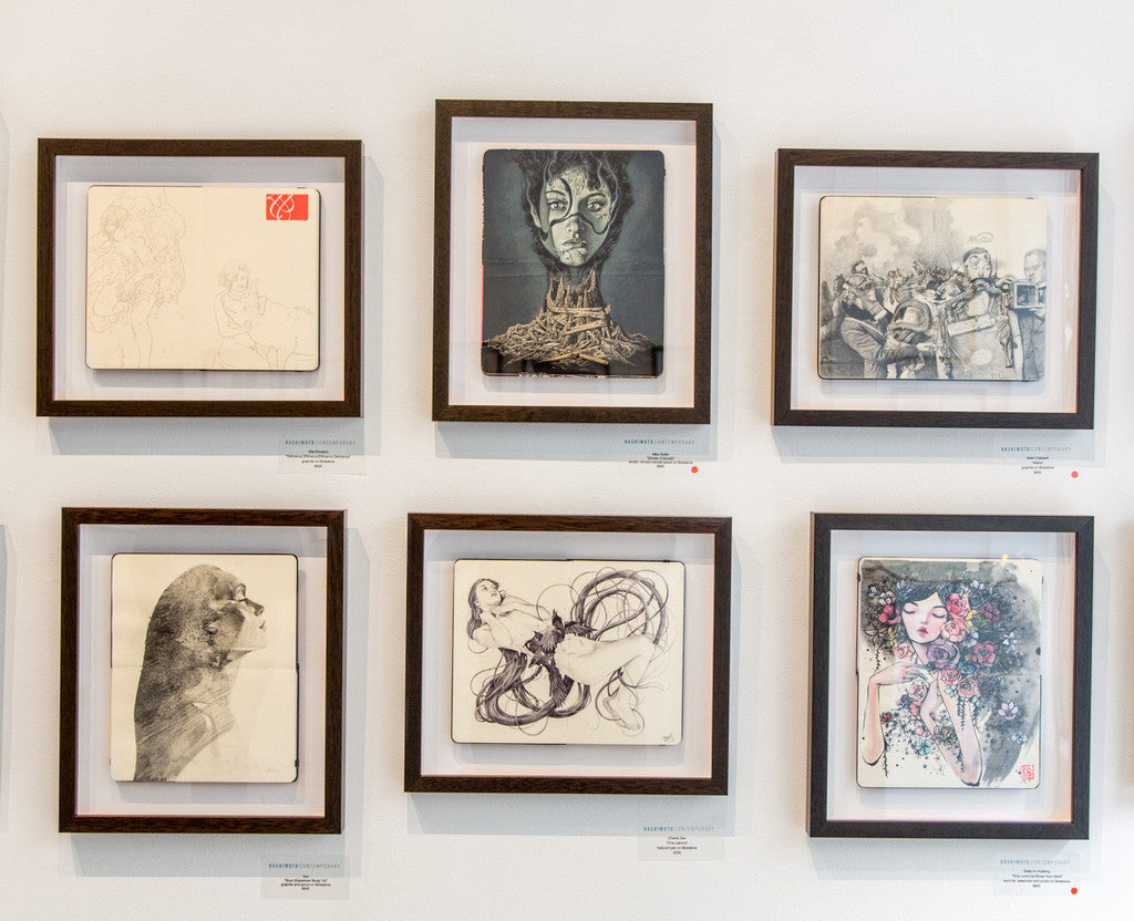 A gallery wall displays six framed graphite and pencil sketches, featuring a portrait, animals, abstract forms, and people by Skye (Elsewhere Study 10). Each piece is set in simple wooden frames on a white wall. Brand: Von.