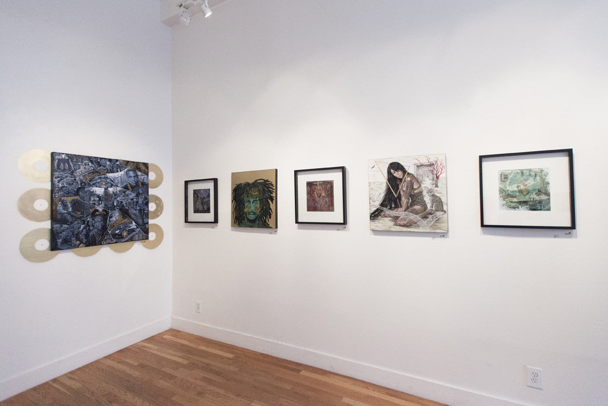 The art gallery interior displays five framed artworks by Serge Gay Jr., featuring a mix of abstract and figurative styles. The wooden flooring and bright lighting accentuate the minimalist decor, highlighting themes from Hustlers Problems.